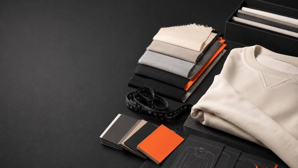 Fabric swatch stack, colour cards and a folded sweatshirt on a studio table
